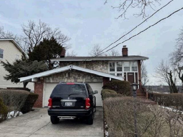 view of front facade with driveway, a chimney, and an attached garage