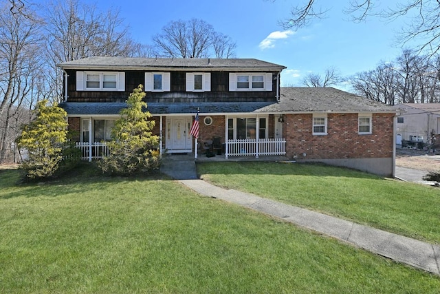 view of front of property featuring covered porch, a front yard, and brick siding