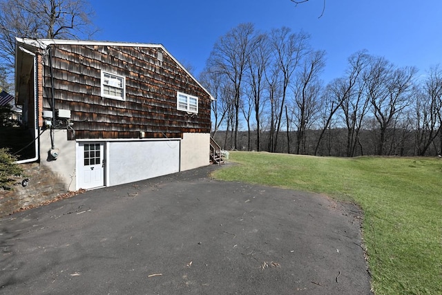 view of property exterior with a detached garage and a yard