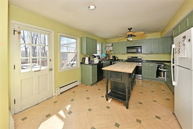 kitchen with gas range, freestanding refrigerator, baseboard heating, black microwave, and green cabinets