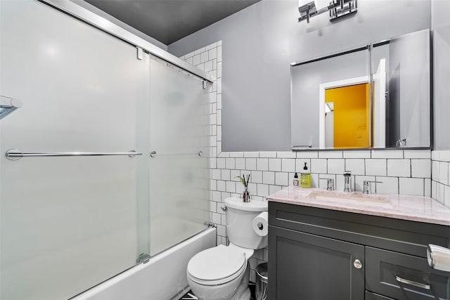 full bathroom featuring toilet, vanity, tile walls, and enclosed tub / shower combo