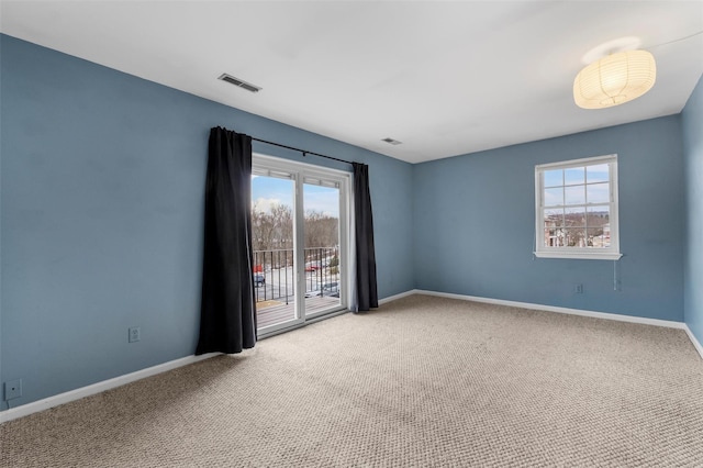 unfurnished room featuring carpet floors, visible vents, and baseboards