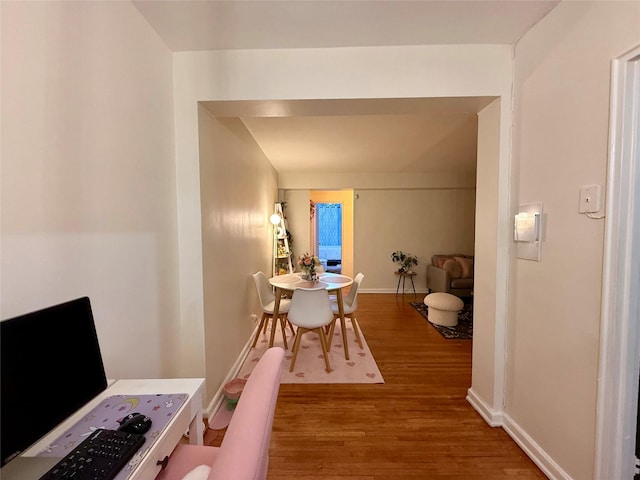 corridor with baseboards and wood finished floors