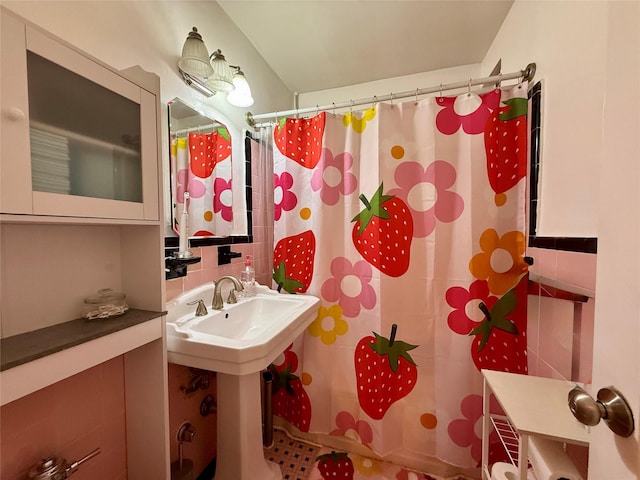 bathroom featuring a shower with shower curtain, a sink, and tile walls