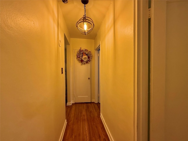 hallway featuring dark wood-type flooring and baseboards