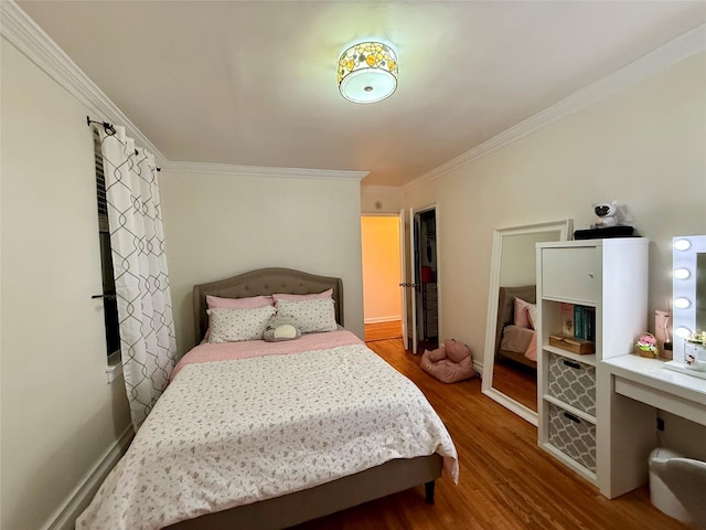 bedroom featuring baseboards, ornamental molding, and wood finished floors