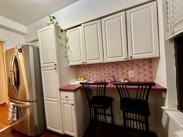 kitchen featuring dark countertops, tasteful backsplash, white cabinets, and freestanding refrigerator