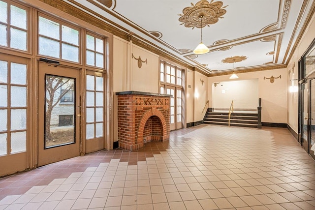 unfurnished living room featuring a wealth of natural light, stairs, a fireplace, and crown molding