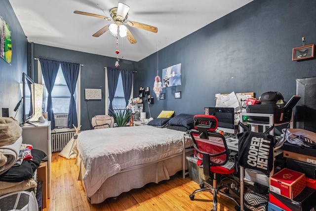 bedroom featuring radiator heating unit, wood-type flooring, and a ceiling fan