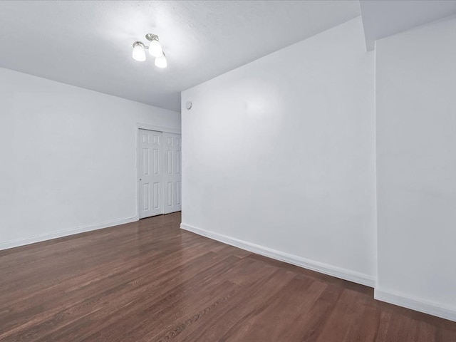 empty room featuring baseboards and dark wood finished floors