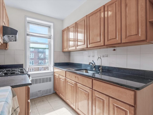 kitchen with extractor fan, a sink, radiator, dark stone counters, and tasteful backsplash