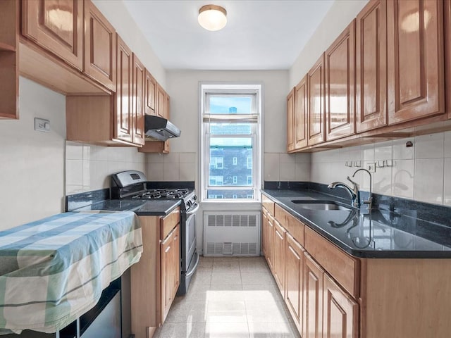 kitchen with radiator heating unit, brown cabinetry, a sink, gas range, and under cabinet range hood