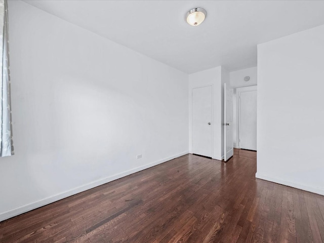 unfurnished room with dark wood-style flooring and baseboards