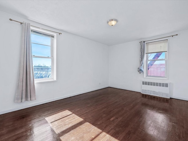 spare room with radiator, plenty of natural light, and hardwood / wood-style floors