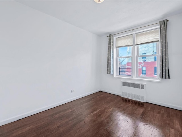 empty room with radiator, baseboards, and dark wood-style flooring