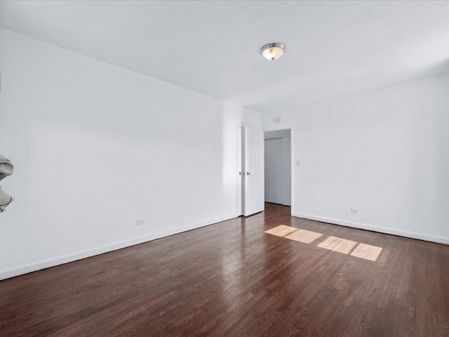 spare room featuring baseboards and wood finished floors