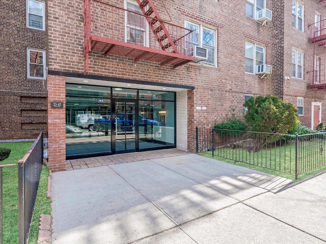 property entrance with fence, cooling unit, and brick siding