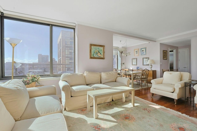 living room with a city view, an inviting chandelier, wood finished floors, and crown molding