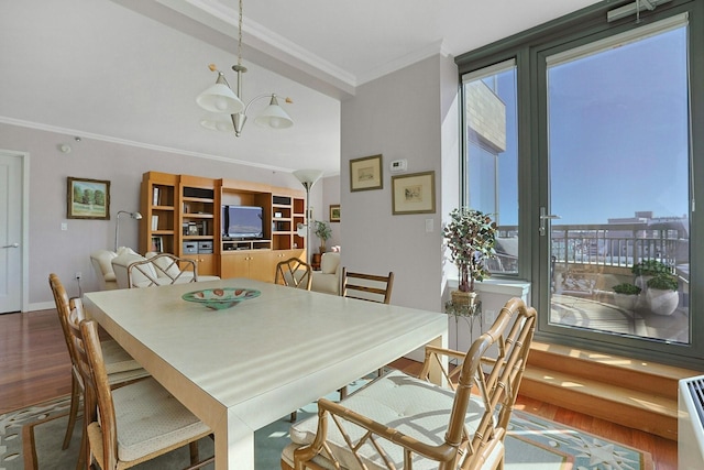 dining area featuring ornamental molding, a wealth of natural light, a notable chandelier, and wood finished floors