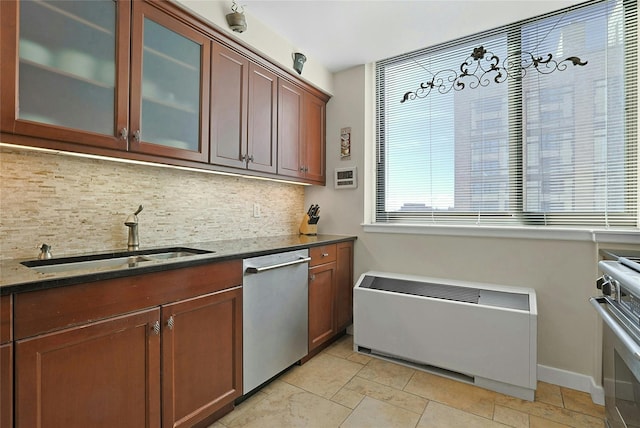 kitchen with dark stone counters, glass insert cabinets, appliances with stainless steel finishes, a sink, and backsplash