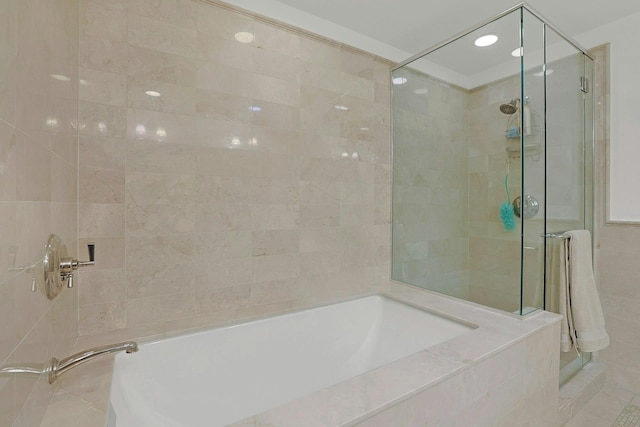 full bath with a stall shower, a garden tub, and tile walls