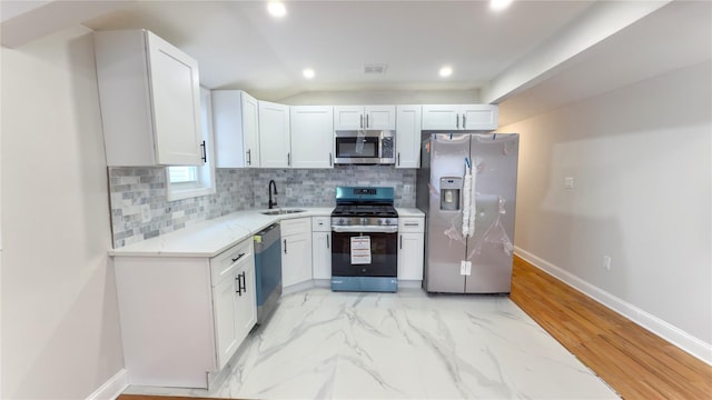 kitchen featuring marble finish floor, appliances with stainless steel finishes, a sink, and decorative backsplash