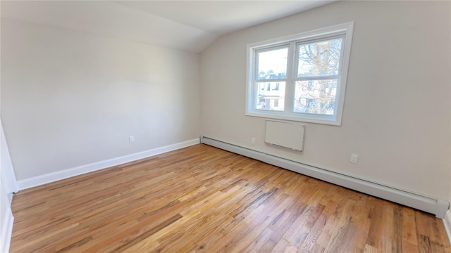 bonus room featuring light wood-style flooring, a baseboard heating unit, vaulted ceiling, and baseboards