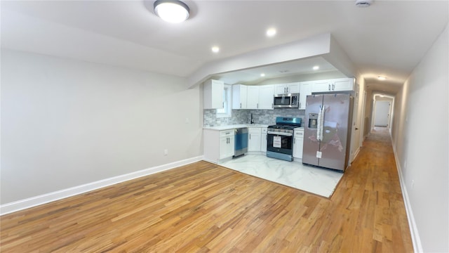 kitchen with stainless steel appliances, light countertops, decorative backsplash, white cabinetry, and vaulted ceiling