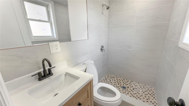 bathroom with tile walls, backsplash, toilet, a stall shower, and vanity