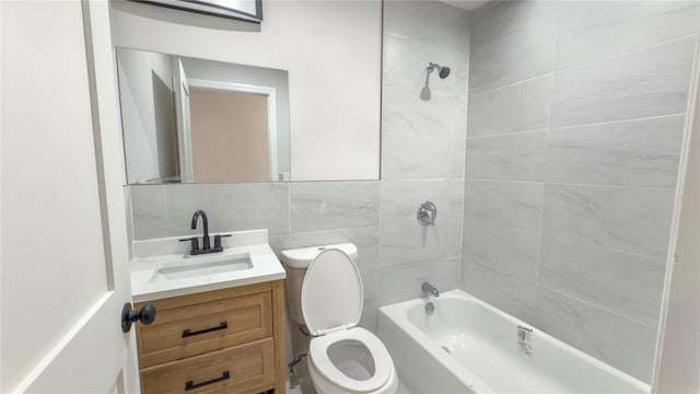 full bath with shower / bathtub combination, toilet, vanity, and tile walls