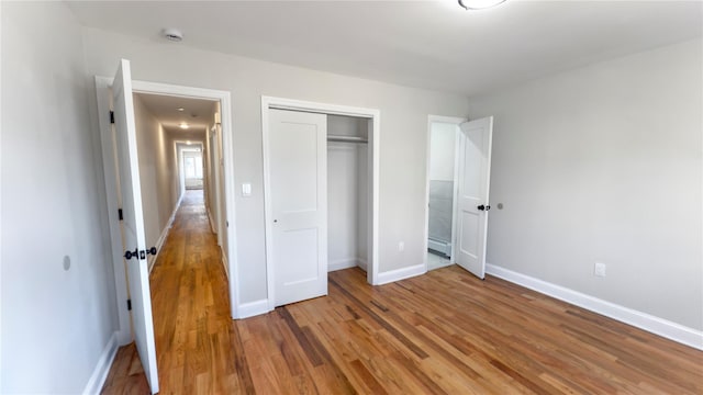 unfurnished bedroom featuring light wood finished floors, a closet, and baseboards