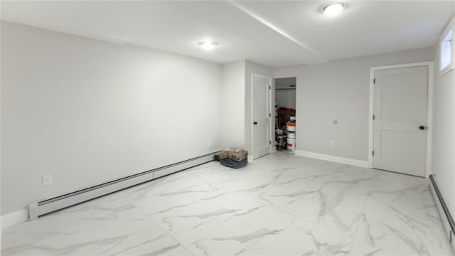 empty room featuring marble finish floor, baseboard heating, and baseboards