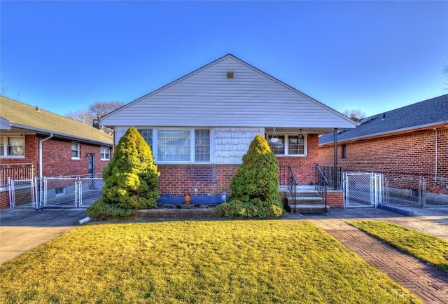 view of front of house with brick siding, covered porch, a gate, fence, and a front lawn