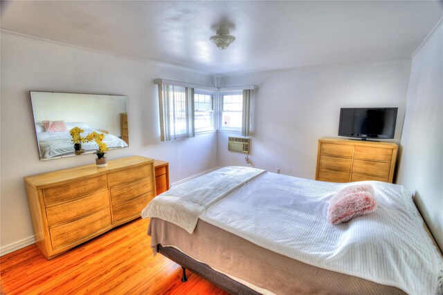 bedroom featuring a wall unit AC and light wood-style floors