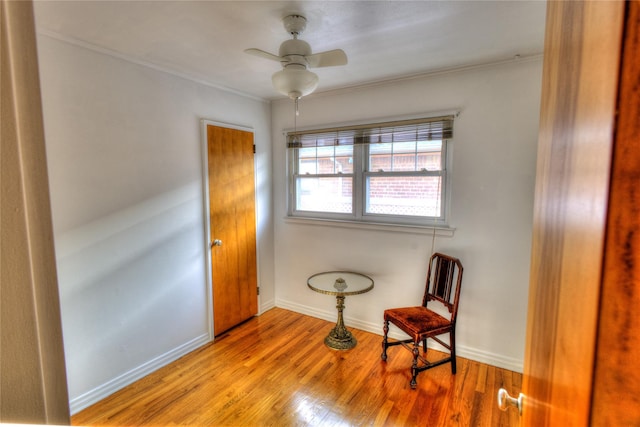 sitting room featuring crown molding, wood finished floors, a ceiling fan, and baseboards