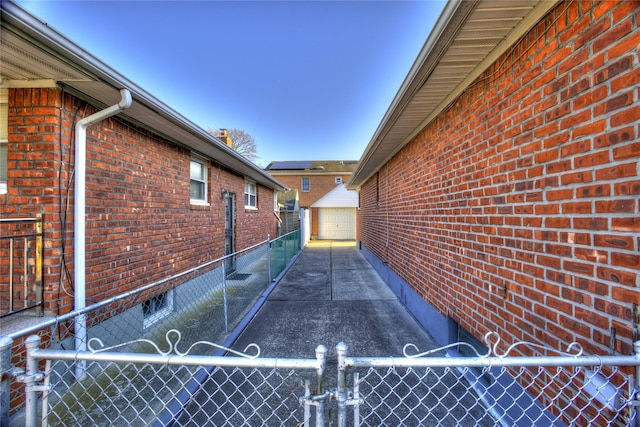 view of home's exterior featuring a detached garage, a gate, fence, an outdoor structure, and brick siding