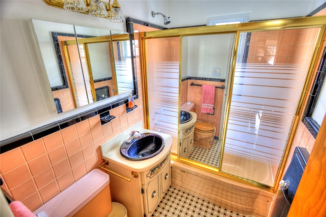 full bath with toilet, enclosed tub / shower combo, tile patterned floors, vanity, and tile walls