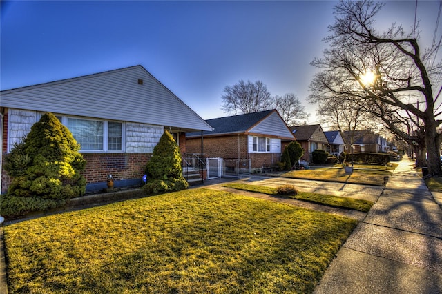 view of front of home featuring a residential view, brick siding, and a front lawn