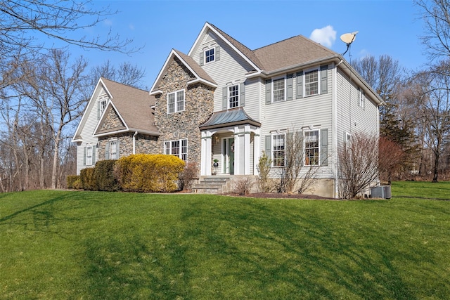 view of front facade with cooling unit, stone siding, and a front lawn