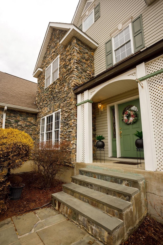 view of exterior entry with stone siding and a porch