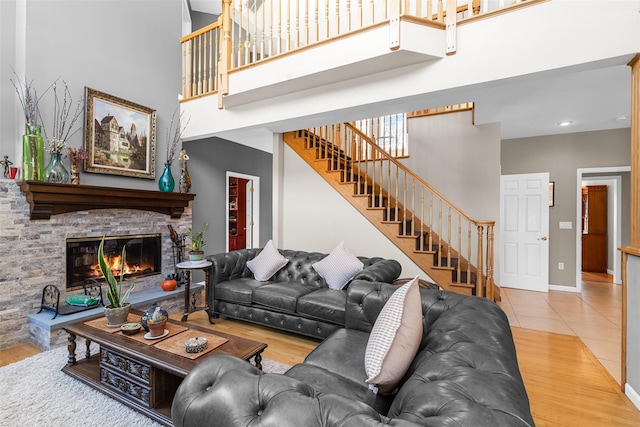 living room with stairway, a fireplace, wood finished floors, and a towering ceiling