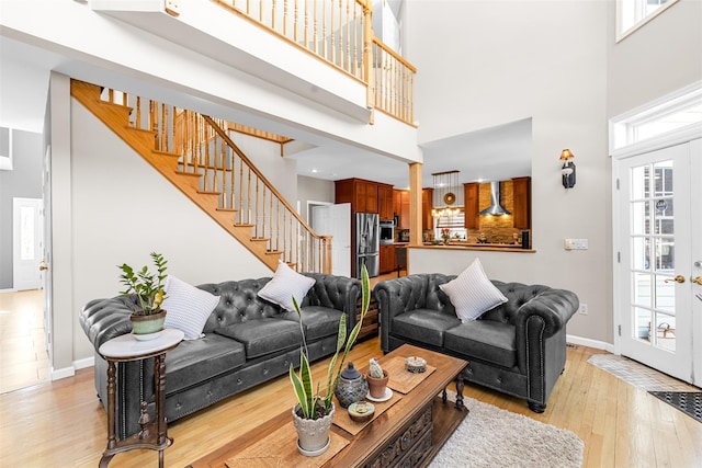 living room featuring french doors, stairway, light wood-style flooring, and baseboards