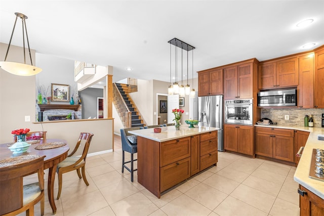 kitchen with brown cabinetry, decorative backsplash, a breakfast bar area, stainless steel appliances, and a fireplace