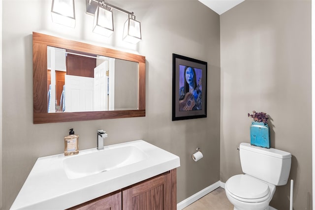 half bath with baseboards, vanity, and toilet