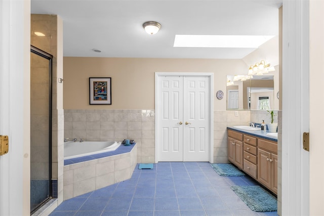 bathroom featuring a sink, tile patterned flooring, tile walls, and a shower stall