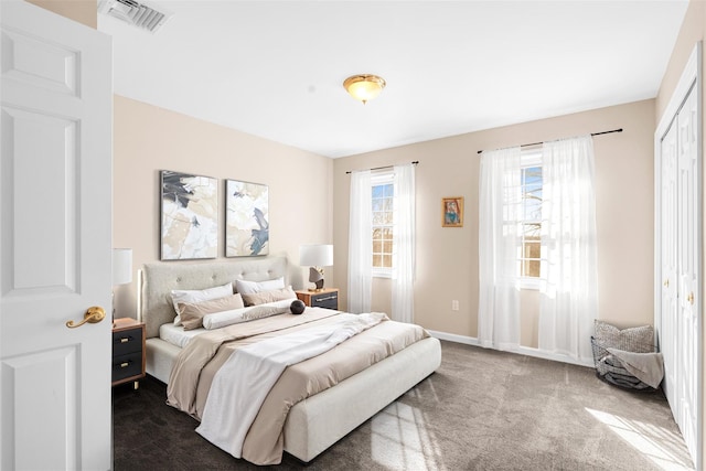 bedroom featuring baseboards, visible vents, dark carpet, and a closet