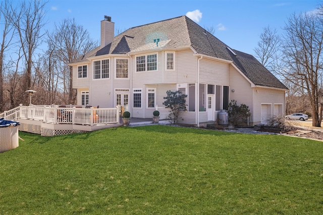 back of property with roof with shingles, a yard, a chimney, a deck, and a garage