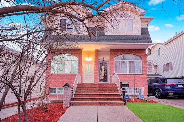 view of front of property featuring a shingled roof and brick siding