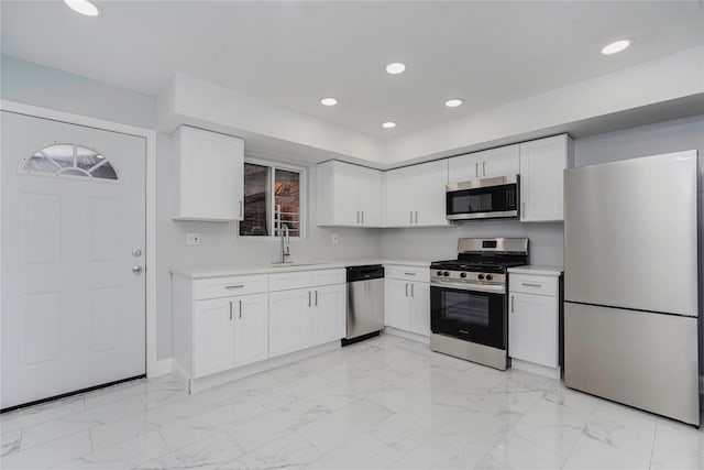 kitchen featuring stainless steel appliances, recessed lighting, light countertops, and a sink