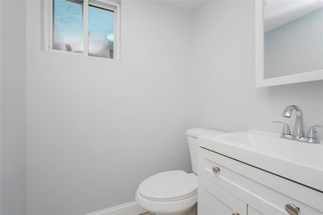 bathroom featuring toilet, baseboards, and vanity